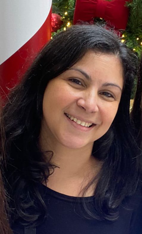 Foto da psicanalista Graziela Peres sorrindo, com fundo neutro